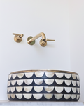 Black and white patterned sink with gold faucet against a white wall
