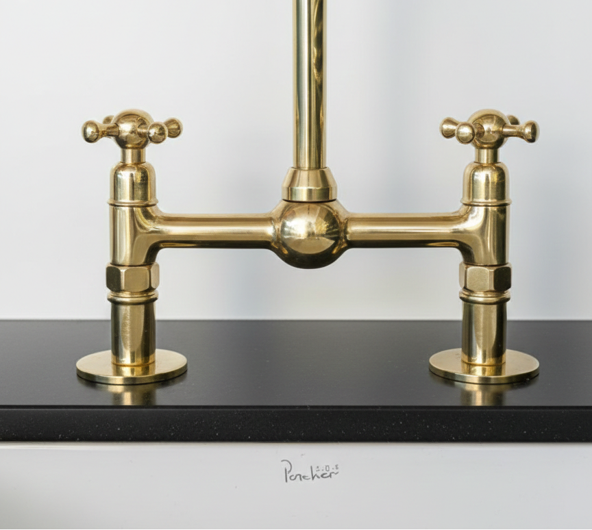 Brass kitchen faucet on a black countertop with a white background