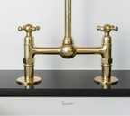 Brass kitchen faucet on a black countertop with a white background