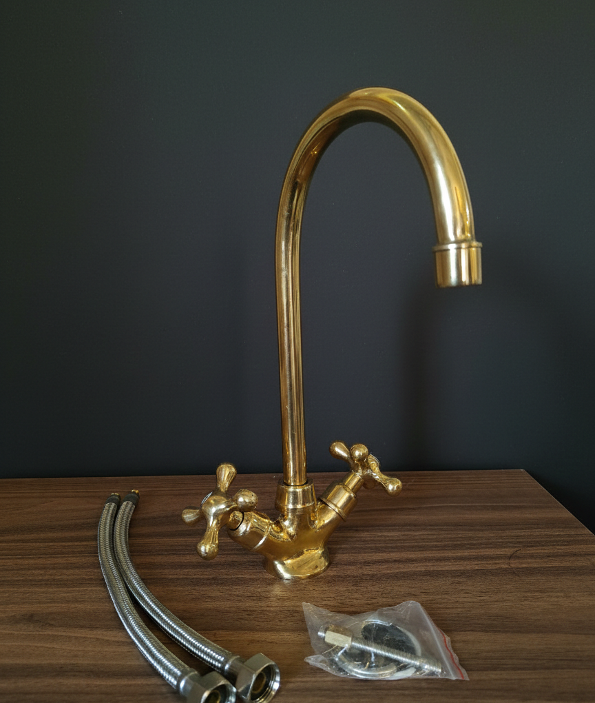 Gold kitchen faucet with hoses and connectors on a wooden surface against a dark background